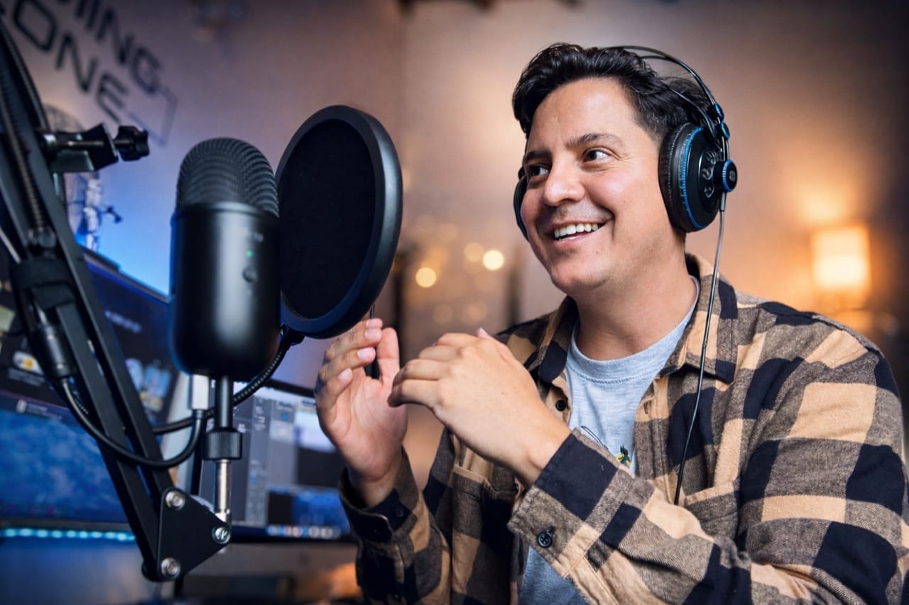 César Orozco grabando frente al micrófono con audífonos puestos